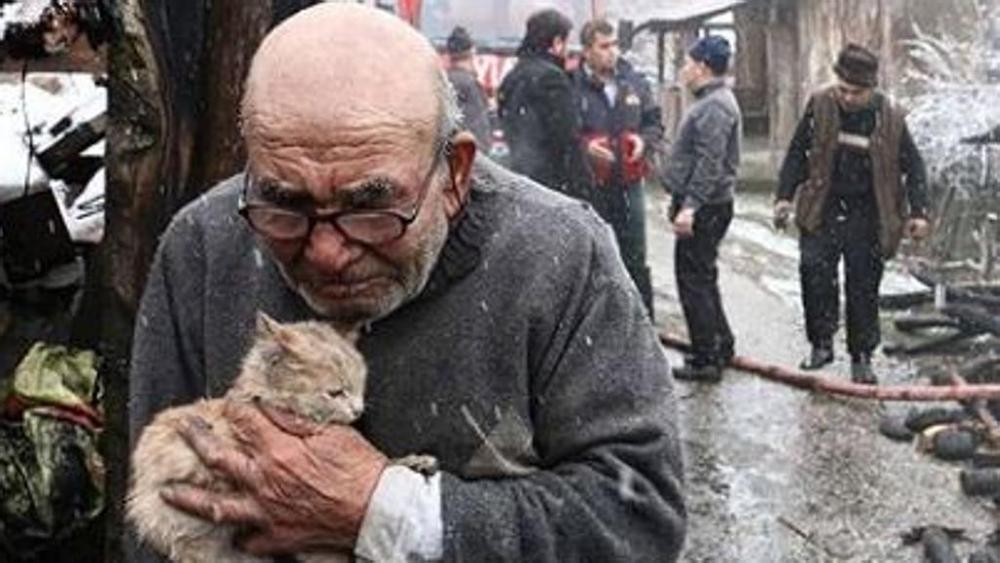 Anziano stringe il gattino a sé dopo un incendio: la foto commuove il web